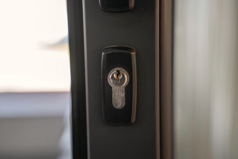 A lock cylinder set in the dark aluminum frame of a glass door