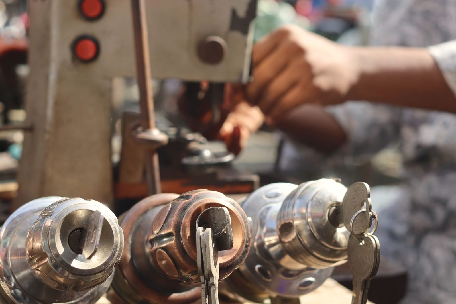 Three brass and chrome lock cylinders with keys, lined up in front of a key machine