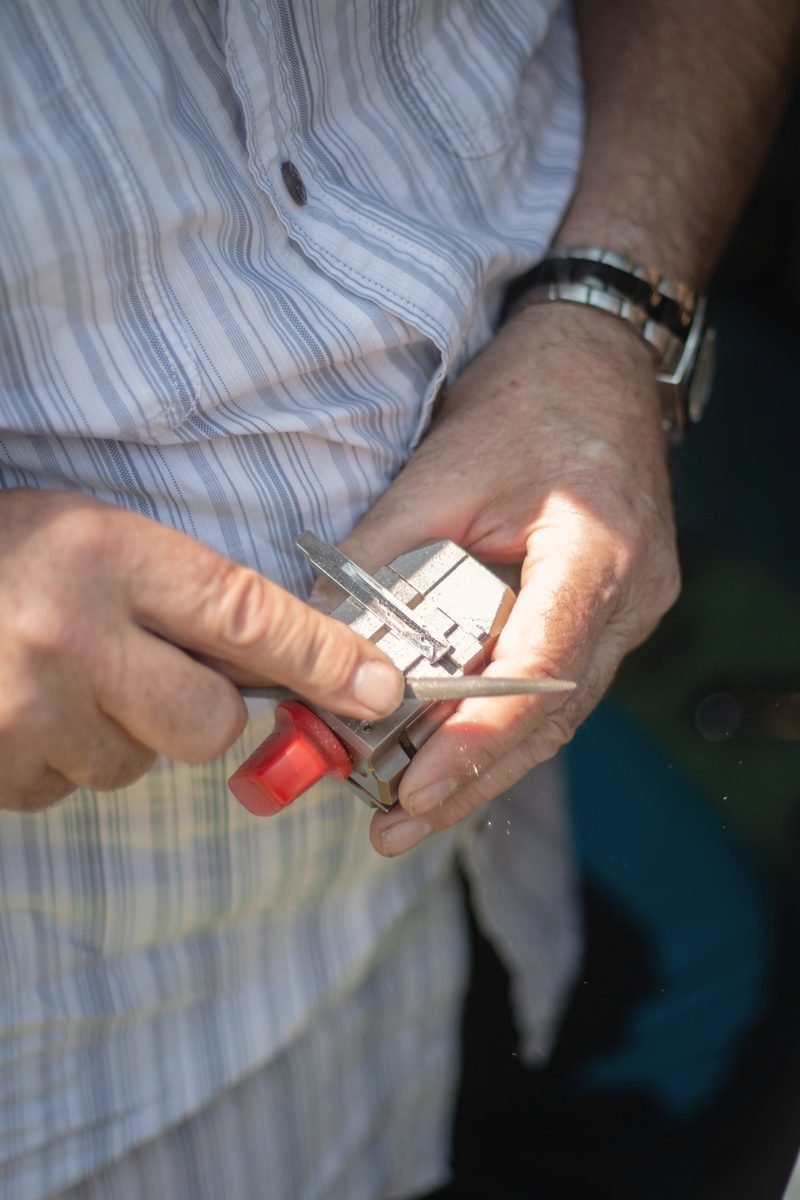 Hands holding a key blade in a small clamp while filing it
