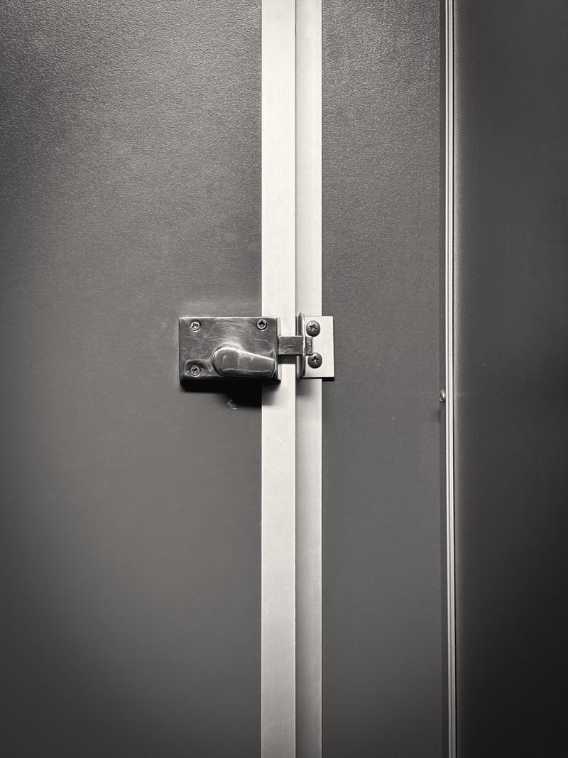 Black and white photo of a steel door with a heavy surface latch