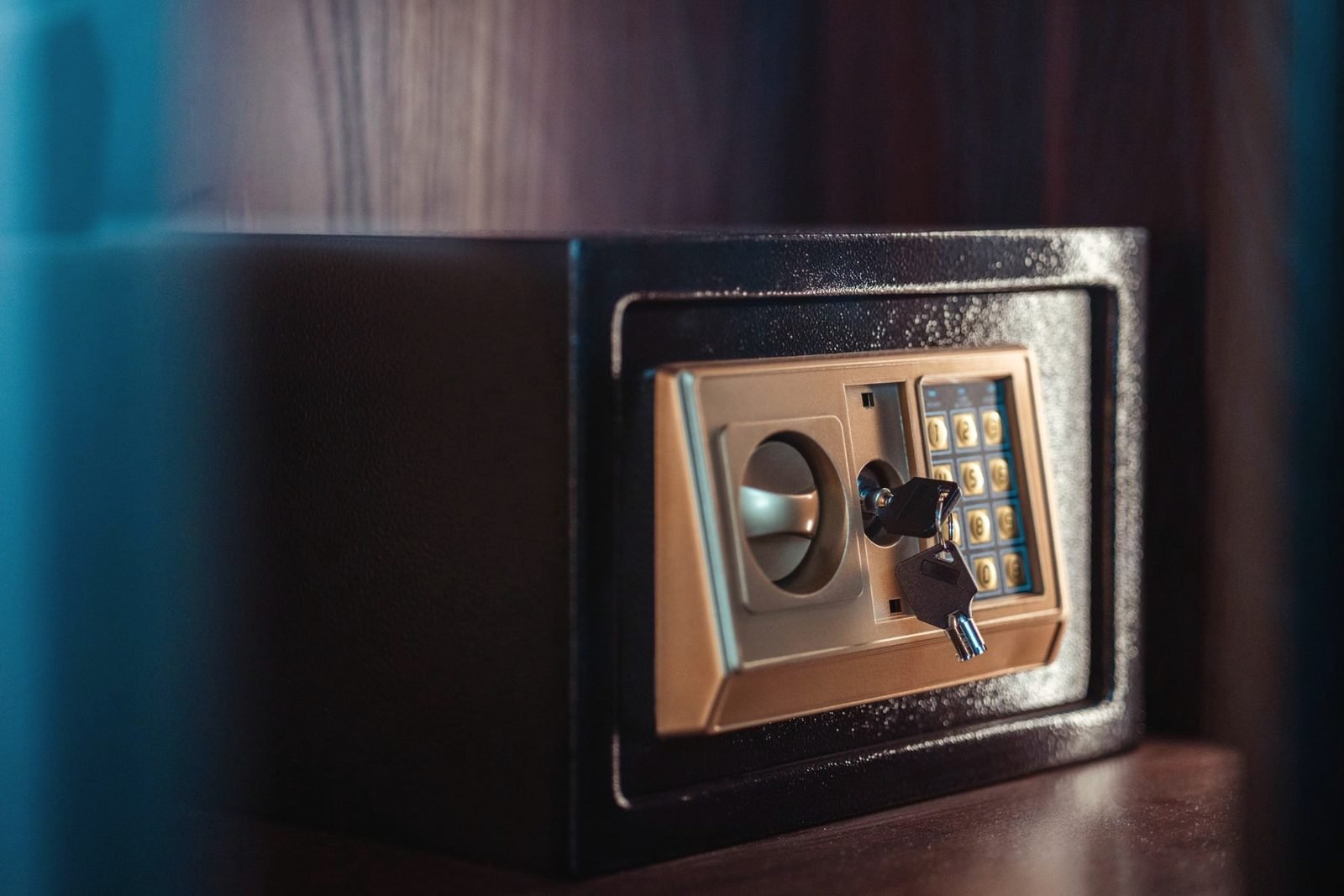 A small black safe with a keypad and a key in the override lock