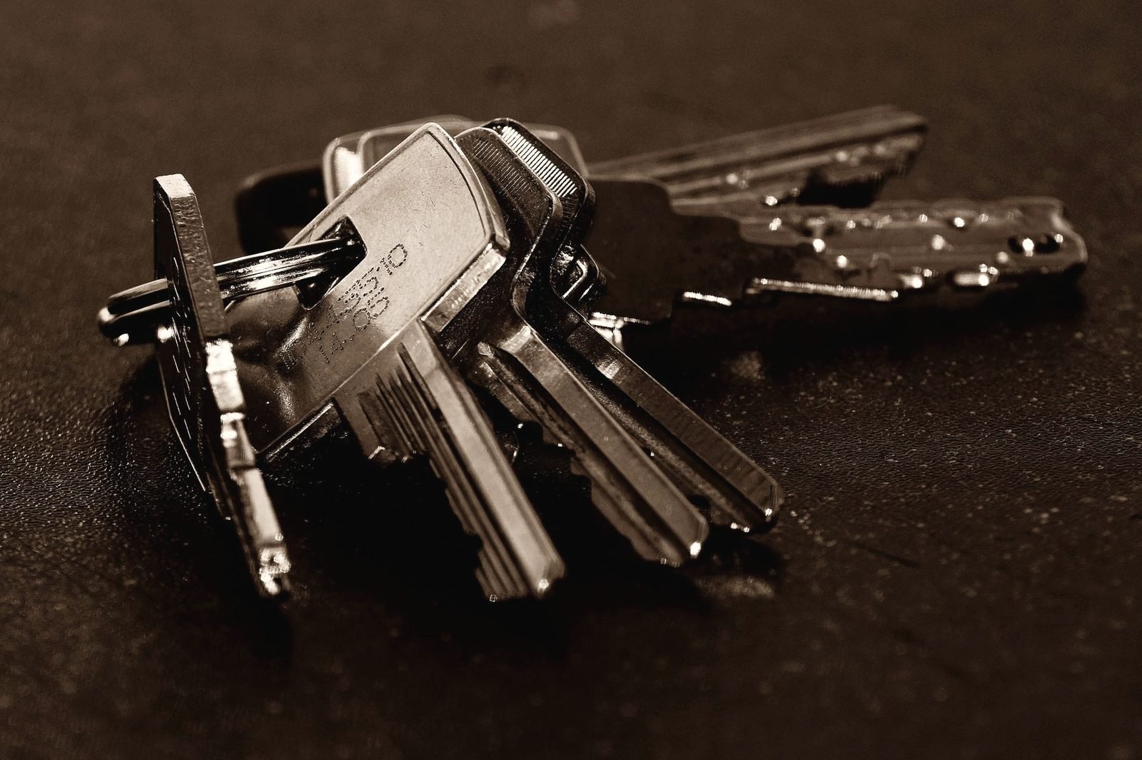 A bunch of cut keys on a ring, lying on a dark surface